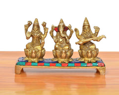 Front view of golden brass Lakshmi, Ganesha and Saraswati on multicolor platform