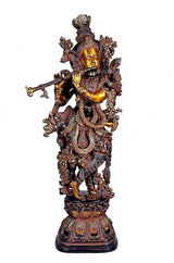 Brass Krishna idol, front view, raised arms and detailed carvings on dark stand