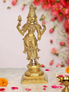 Brass standing Lakshmi goddess idol with four arms, ornate detailing, on pedestal.