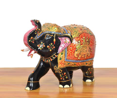 Wooden elephant showpiece, angled side view, red and green panels with painted motifs