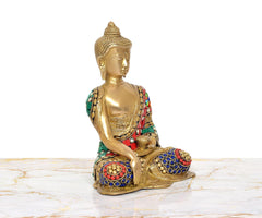 Brass Buddha statue angled view, seated with multicolor jeweled robe and hands posed
