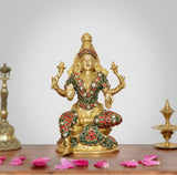 Brass Lakshmi goddess statue, seated with four arms and jeweled red-green detailing