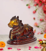 Seated Nandi bull statue, dark brown with gold-toned face and ornate armor details