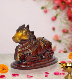 Seated Nandi bull statue, dark brown with gold-toned face and ornate armor details
