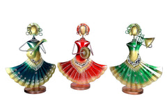 Three iron folk musician figurines with red, green, and teal skirts and brass instruments