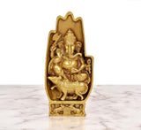 Golden brass Ganesha statue, frontal view, blessing pose and ornate relief on base.