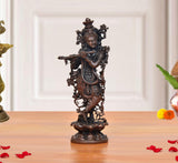 Copper Krishna playing flute figurine, ornate headdress, standing on decorative base.