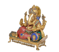 Side view brass Lord Ganesha idol with blue-red patterned robe, trunk raised, and jeweled crown