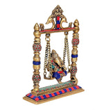 Angled view of brass Ganesha swing idol with colorful ornaments on gold frame