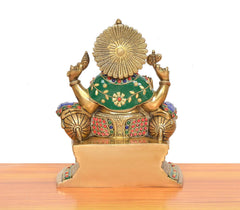 Back view of brass Ganesha statue with circular halo and multicolor green-and-red attire