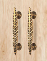 Brass leaf door handle pair in golden, two bars with round plates on light wood