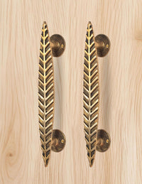 Brass leaf door handle pair in golden, two bars with round plates on light wood