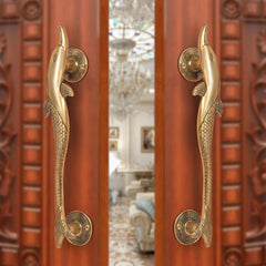 Brass door handle pair with dolphin and fish design, golden finish on door
