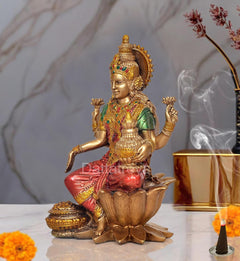 Lakshmi goddess resin statue side view, gold headdress, green-red outfit, seated on lotus