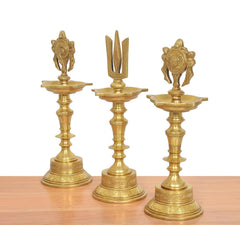Golden brass diya shankh oil lamp trio showing flame bowls and emblem finials