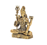 Brass Lord Shiva figurine seated with trident, right hand raised holding small drum.