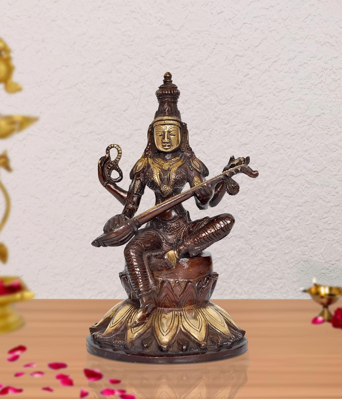 Brass Saraswati idol seated on lotus, holding veena and raised hand gestures.