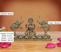 Bronze Lakshmi statue seated between elephants; 3.5 in height, ornate patterned base.