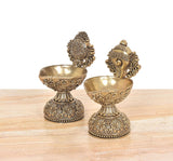 Brass diya shankh oil lamp stand pair, angled view of sculpted heads and patterned bases