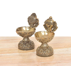 Brass diya shankh oil lamp stand pair, angled view of sculpted heads and patterned bases