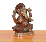 Brass Ganpati Bappa murti, angled view; curved trunk, patterned clothing, metal detailing.