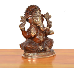 Brass Ganpati Bappa murti, angled view; curved trunk, patterned clothing, metal detailing.