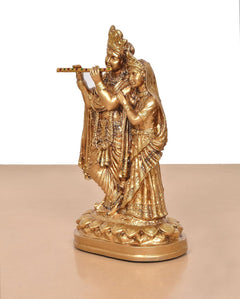 Golden Radha Krishna idol, side view with flute held near mouth and ornate dress