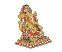 Brass Ganesha idol seated, multicolor gem-like accents on trunk and arms, striped base