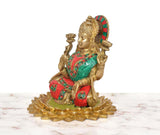 Brass Lakshmi idol side view, teal sari and red garment with green gemstone-like border