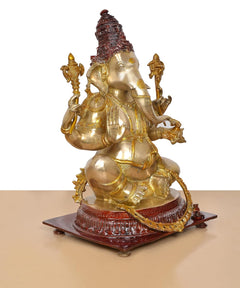 Brass Ganpati Bappa statue side view, seated four-armed pose with red base