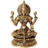 Brass Lakshmi idol, seated with four arms, ornate jewelry, lotus base.