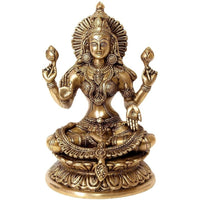 Brass Lakshmi idol, seated with four arms, ornate jewelry, lotus base.