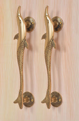 Lower view of two golden brass dolphin fish door handles on round rosettes