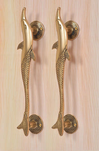 Lower view of two golden brass dolphin fish door handles on round rosettes