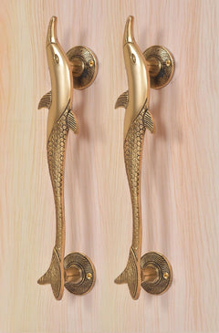 Lower view of two golden brass dolphin fish door handles on round rosettes