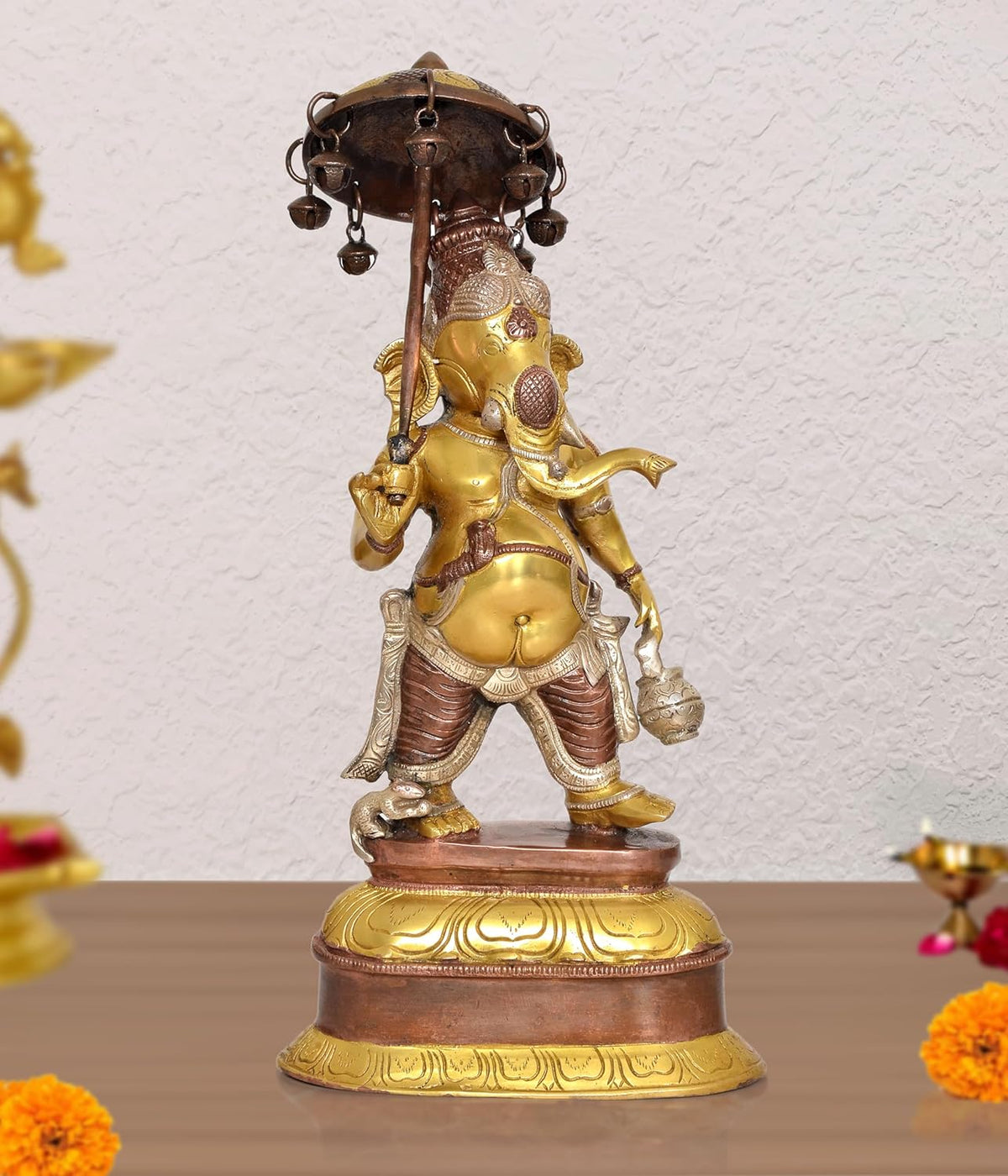 Brass Ganesha idol holding a parasol, one hand raised, gold and brown details