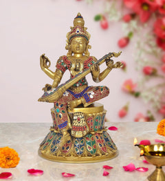 Brass Saraswati idol seated on lotus, playing veena, jeweled red blue green details