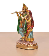 Resin Radha Krishna idol—angled view, Krishna holding flute beside Radha, multicolour robes