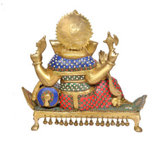 Rear view brass Ganesha idol showing decorated back, blue-and-red cloth, and hanging bells