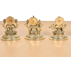 Brass Lakshmi Ganesha Saraswati idols, rear view of three seated figures, gold-tone