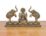 Side view of Lakshmi statue with elephants; ornate brass base and detailed engravings.