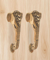 Brass Ganesha face door handle pair, curved striped stems with carved end caps.
