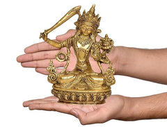 Brass Manjushree statue in hands, small tabletop deity with raised arm and crown