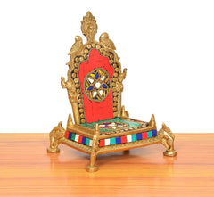 Brass pooja chowki angled view, red panel with deity emblem, multicolor striped base