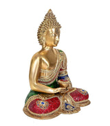 Side view brass Buddha meditation idol, gold body and multicolor jeweled robe on cushion seat.