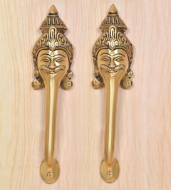 Golden brass door handle pair with smiling face head motifs on the plates