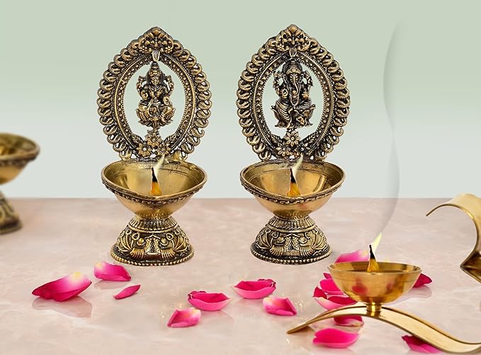 Brass Lakshmi and Ganesha diya oil lamps, two standing holders with small flames