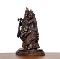 Brass Radha Krishna idol, three-quarter angle showing draped garments and pedestal base.