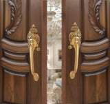 Brass long-neck door handle pair with ornate face heads, golden finish