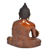 Gold Buddha statue from behind, brown robe with intricate carvings, black hair bun